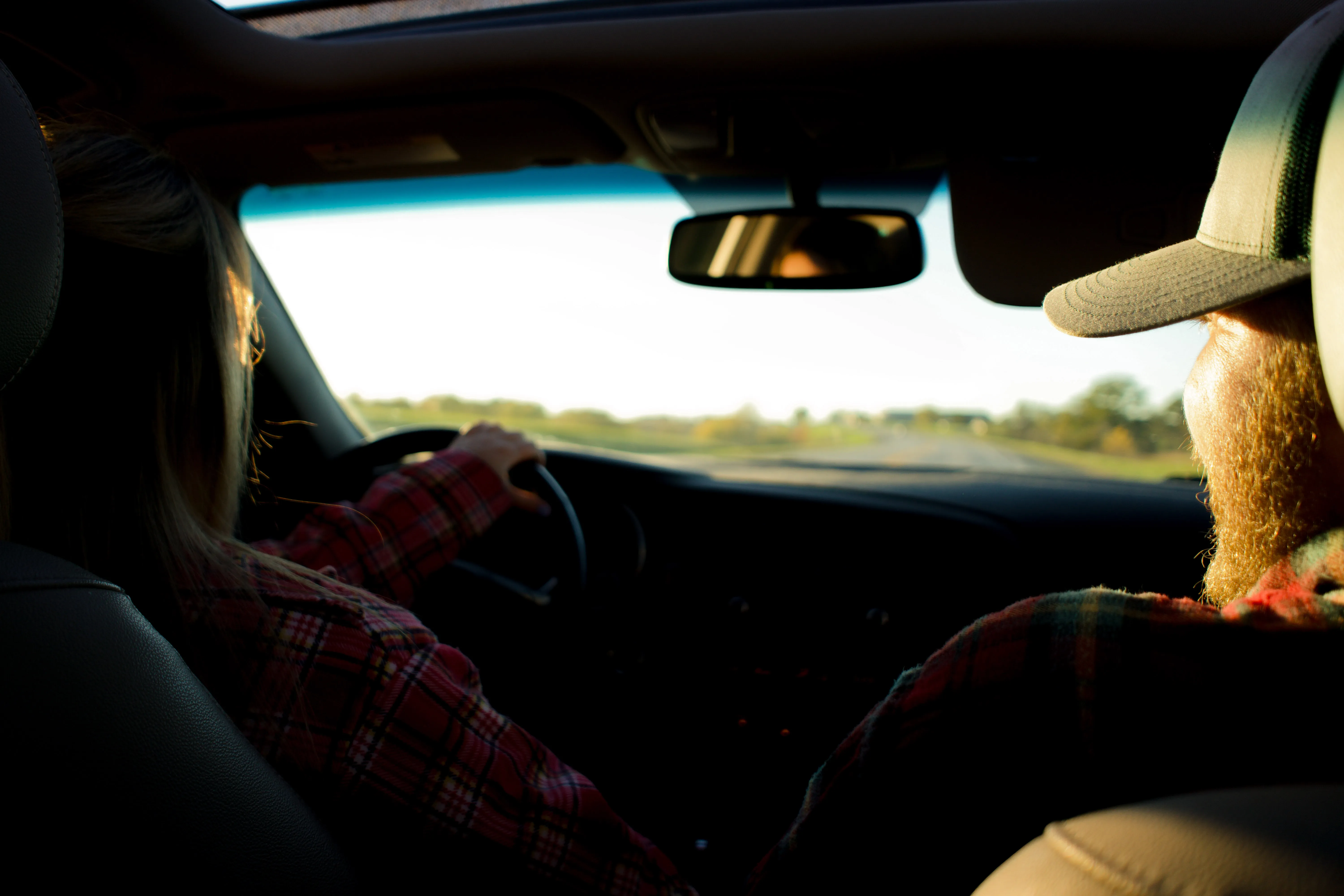 A woman driving a car with a man riding shotgun, smiling at her.