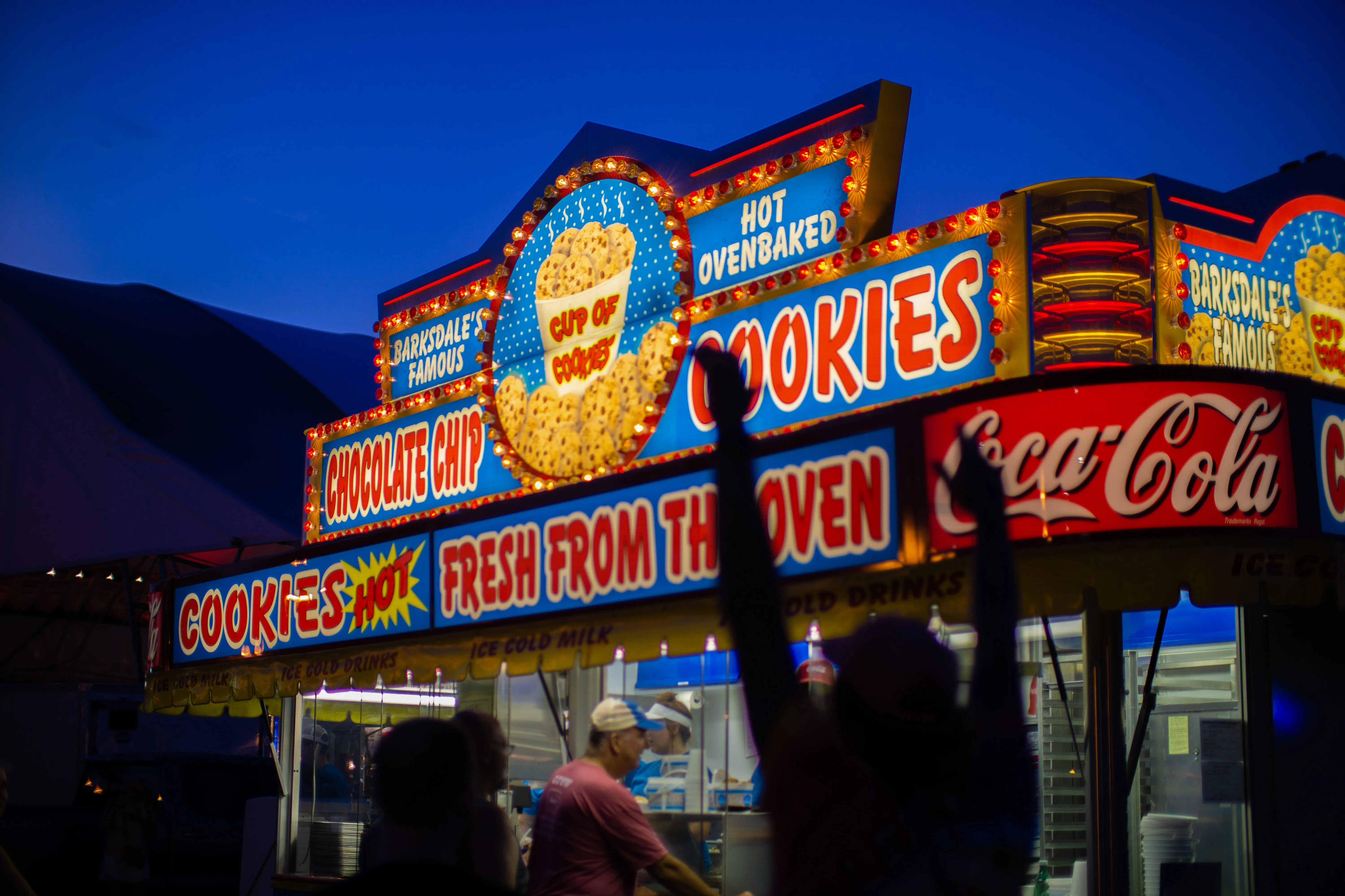 A man raising his arms in celebration as he approaches the Barksdales cookie stand at the Iowa State Fair.