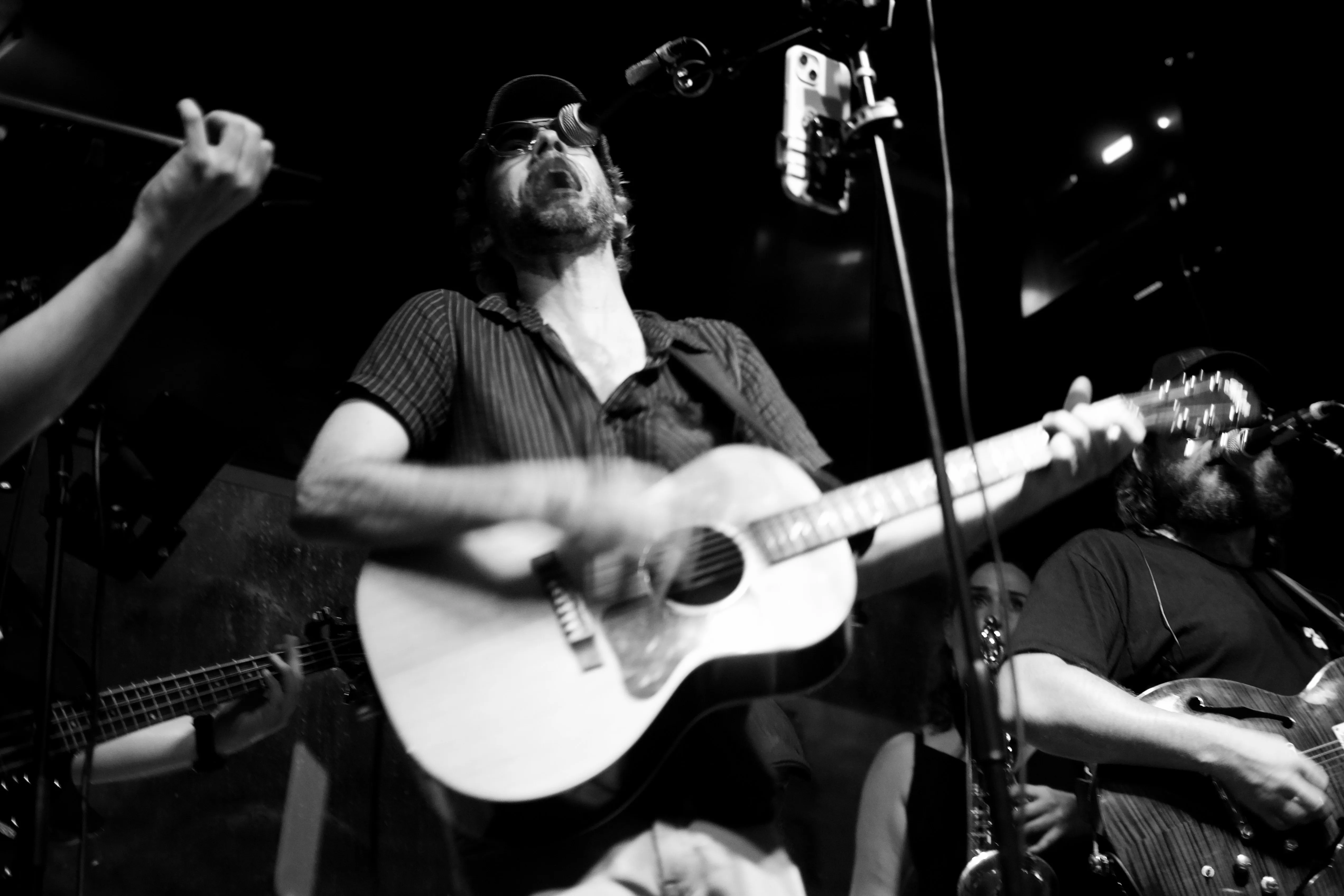 A singer throwing his head back and playing guitar.