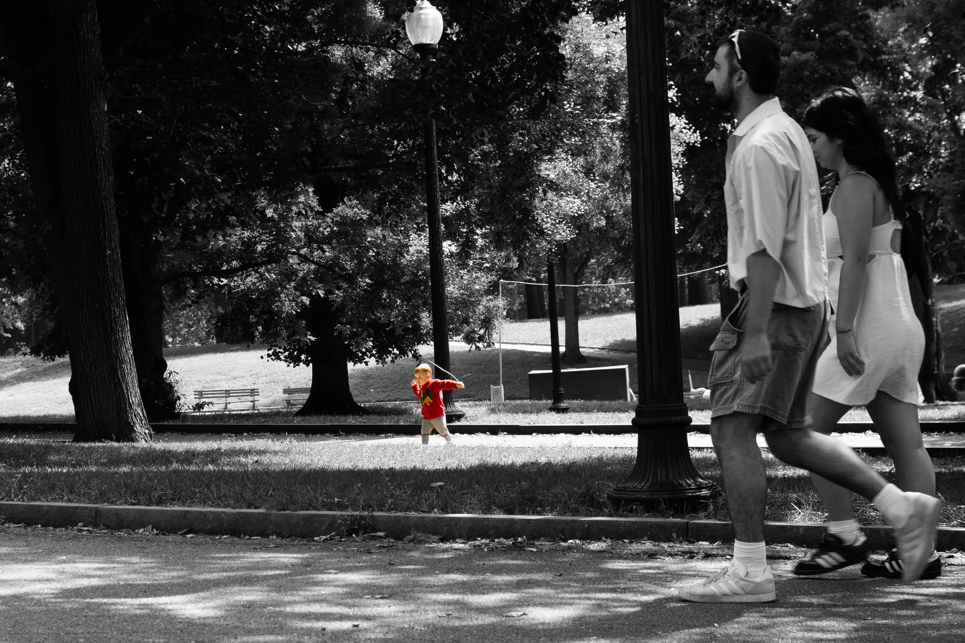 A child in a park swinging a stick.