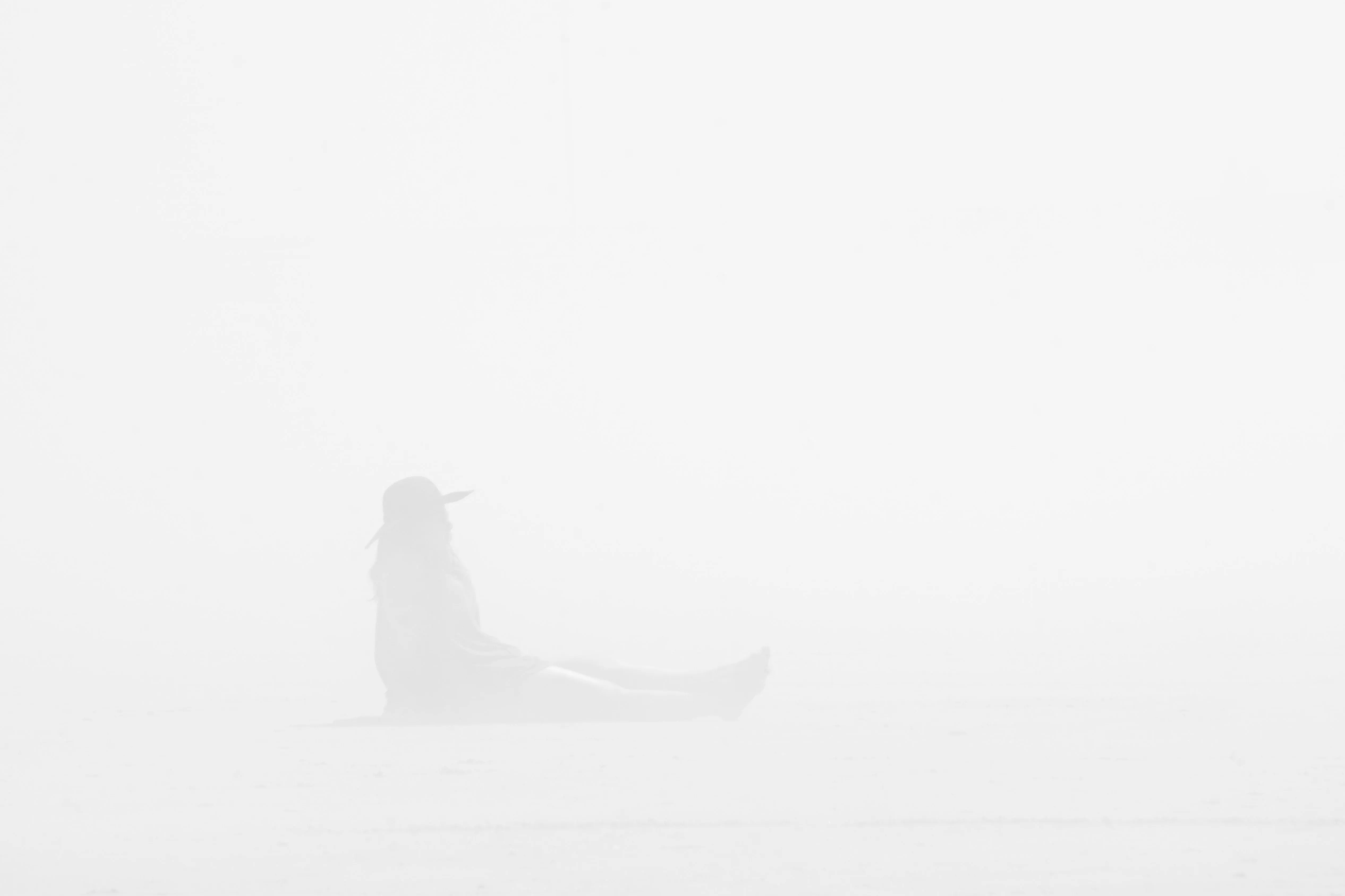 A woman sitting on a hazy beach.