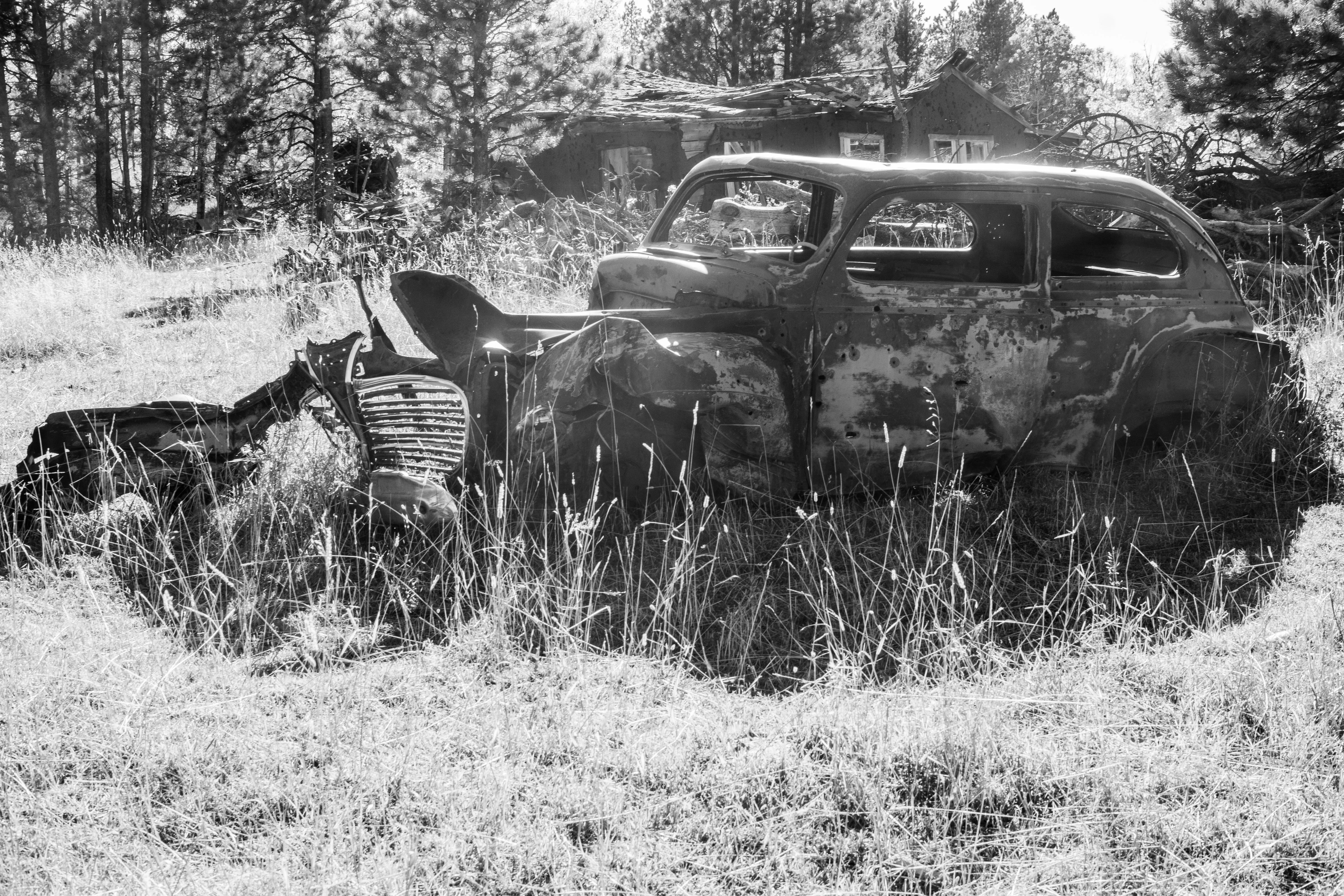 An old rusted out car riddled with bullet holes.