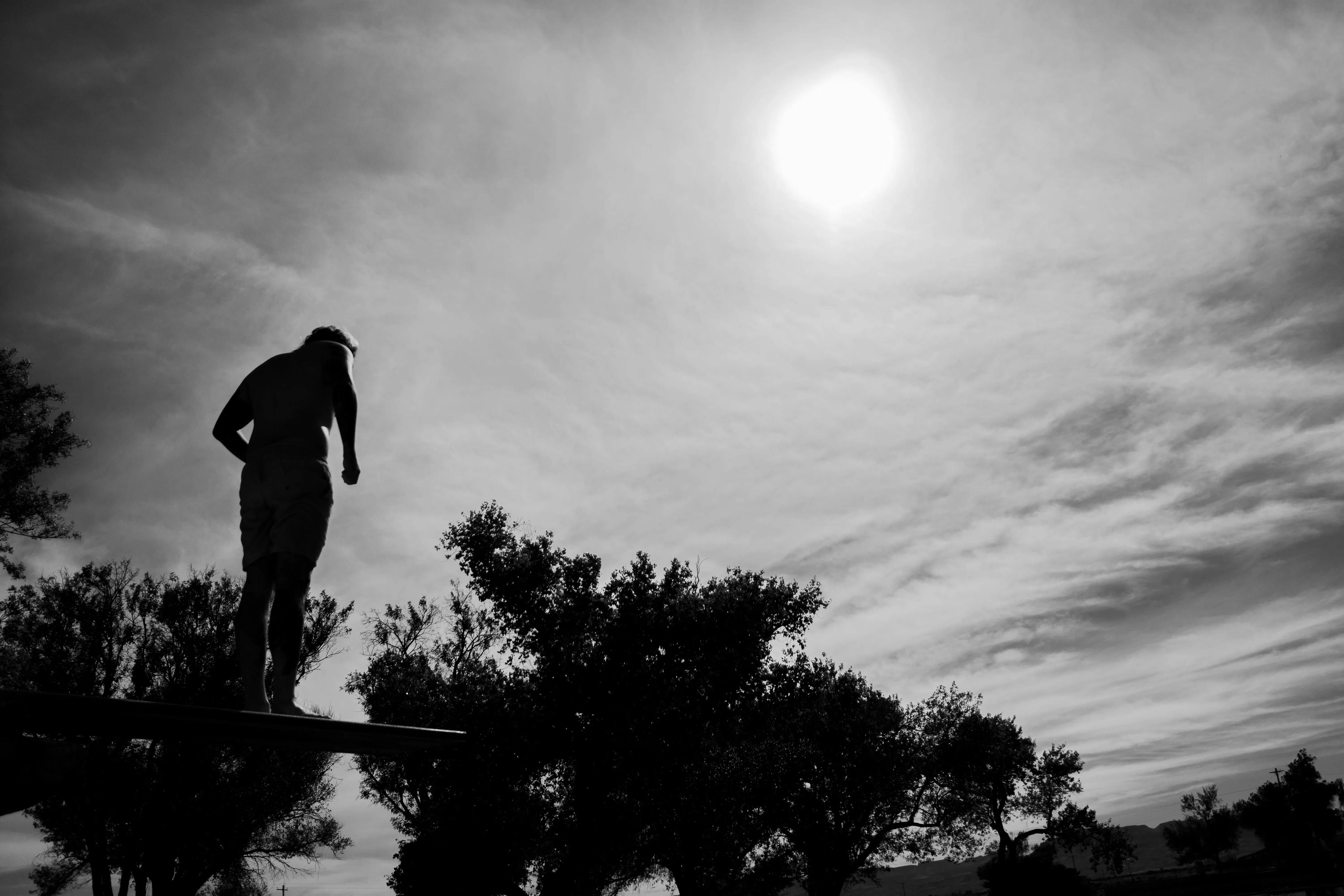 A man standing a diving board, looking nervous.