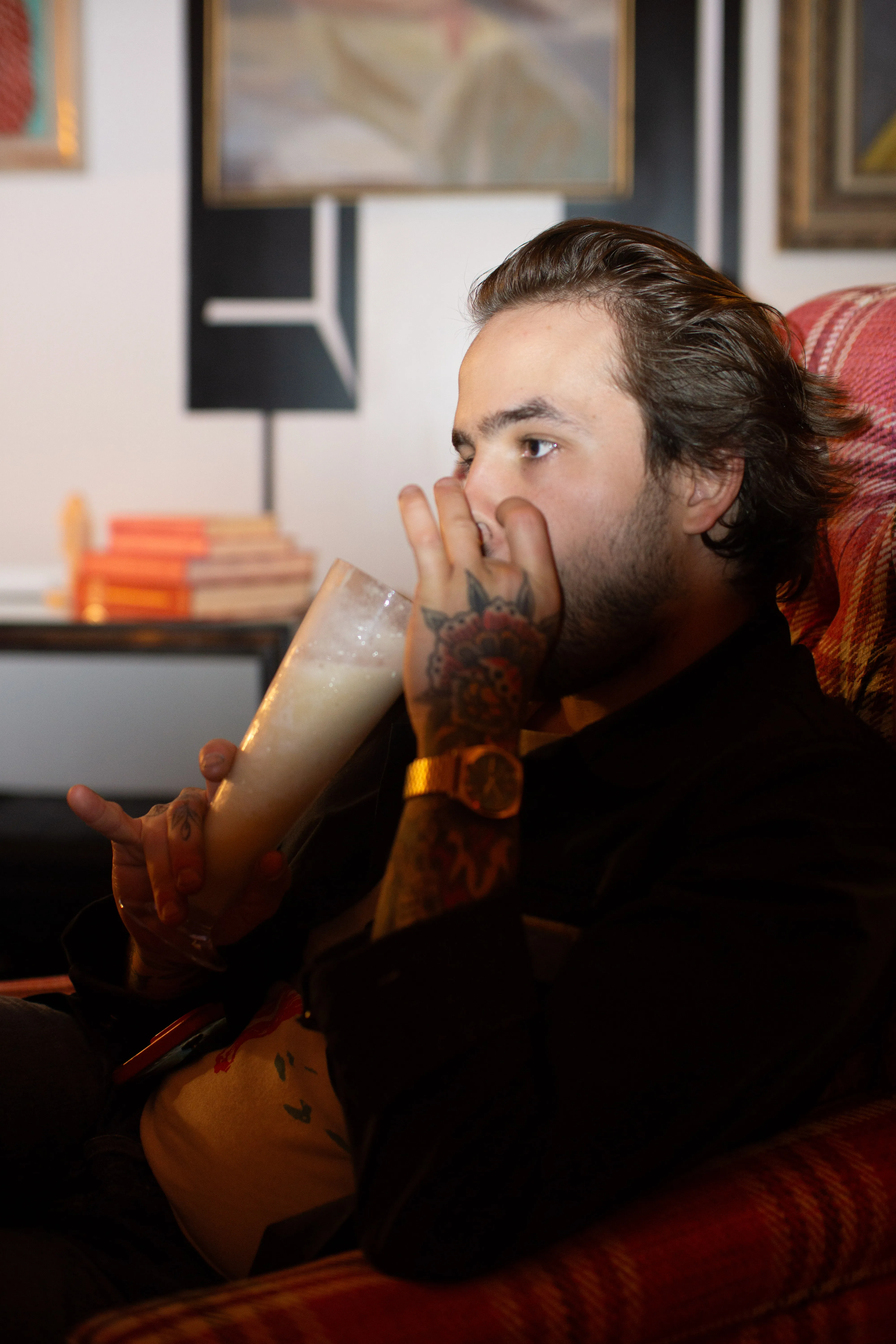 A man sitting in a plush chair drinking a cocktail.