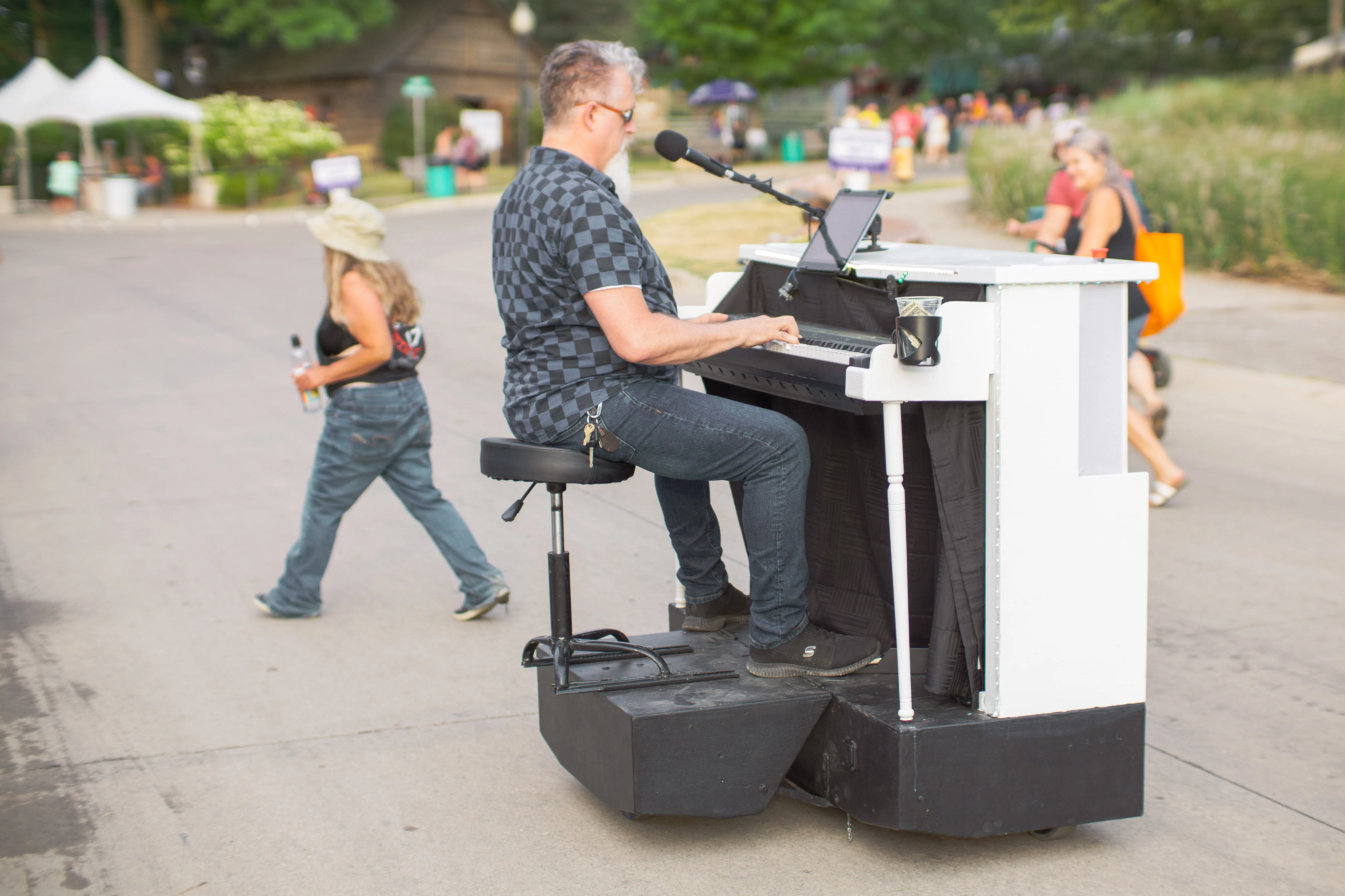 A man playing a moving piano as it rolls down the street.