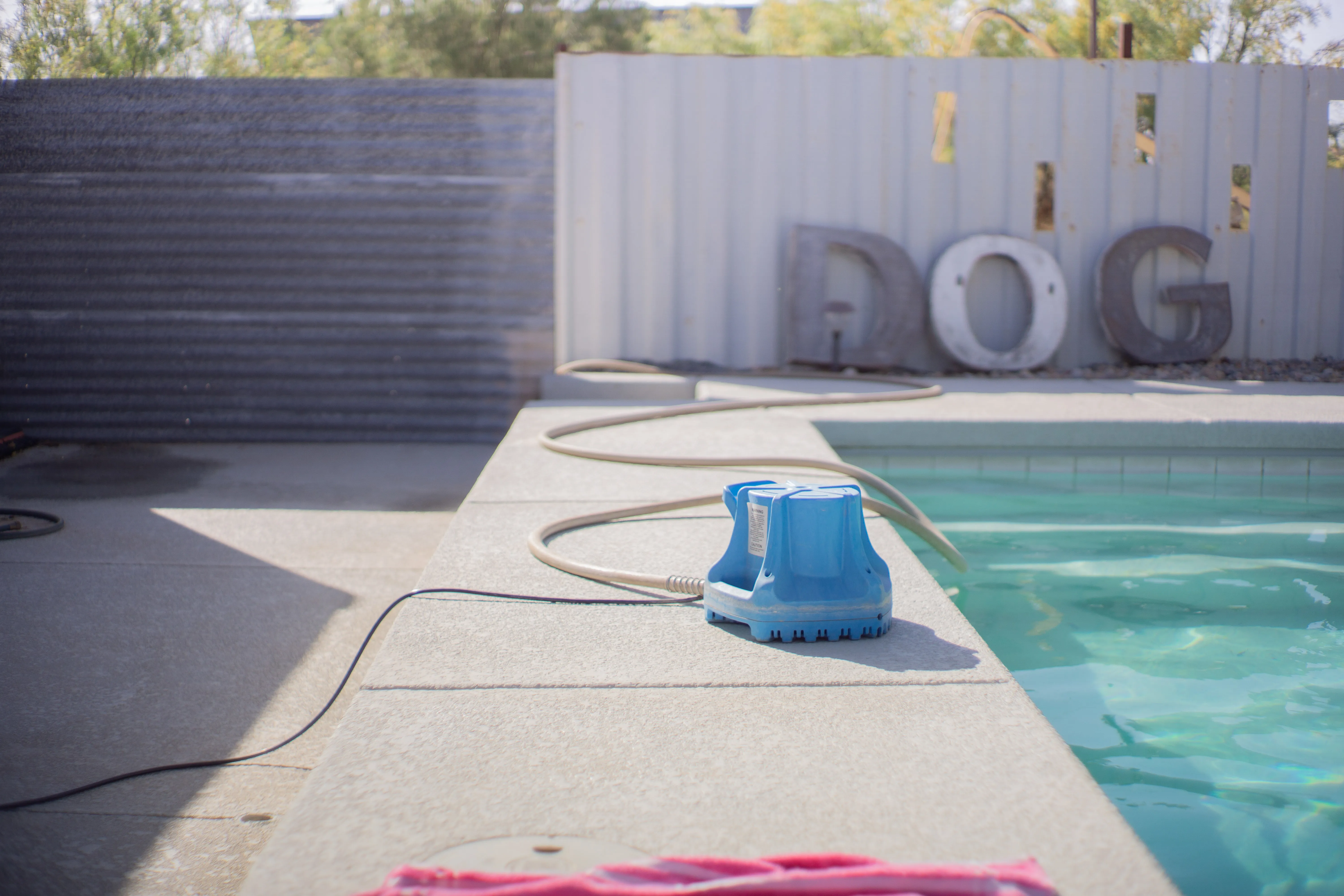 A pool cleaning machine sitting on the ledge next to the pool.