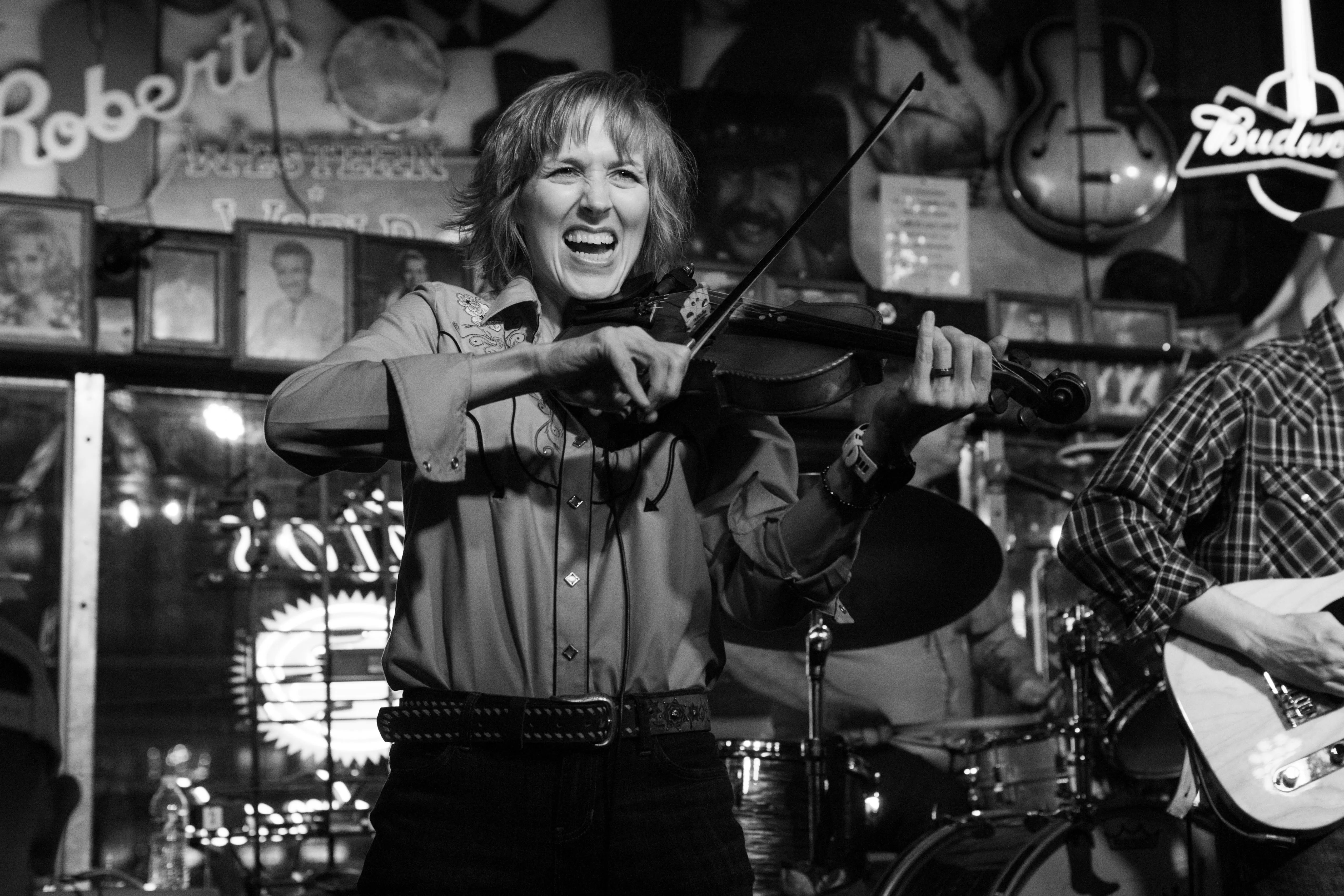 A fiddle player playing and grinning at Robert's Western World.