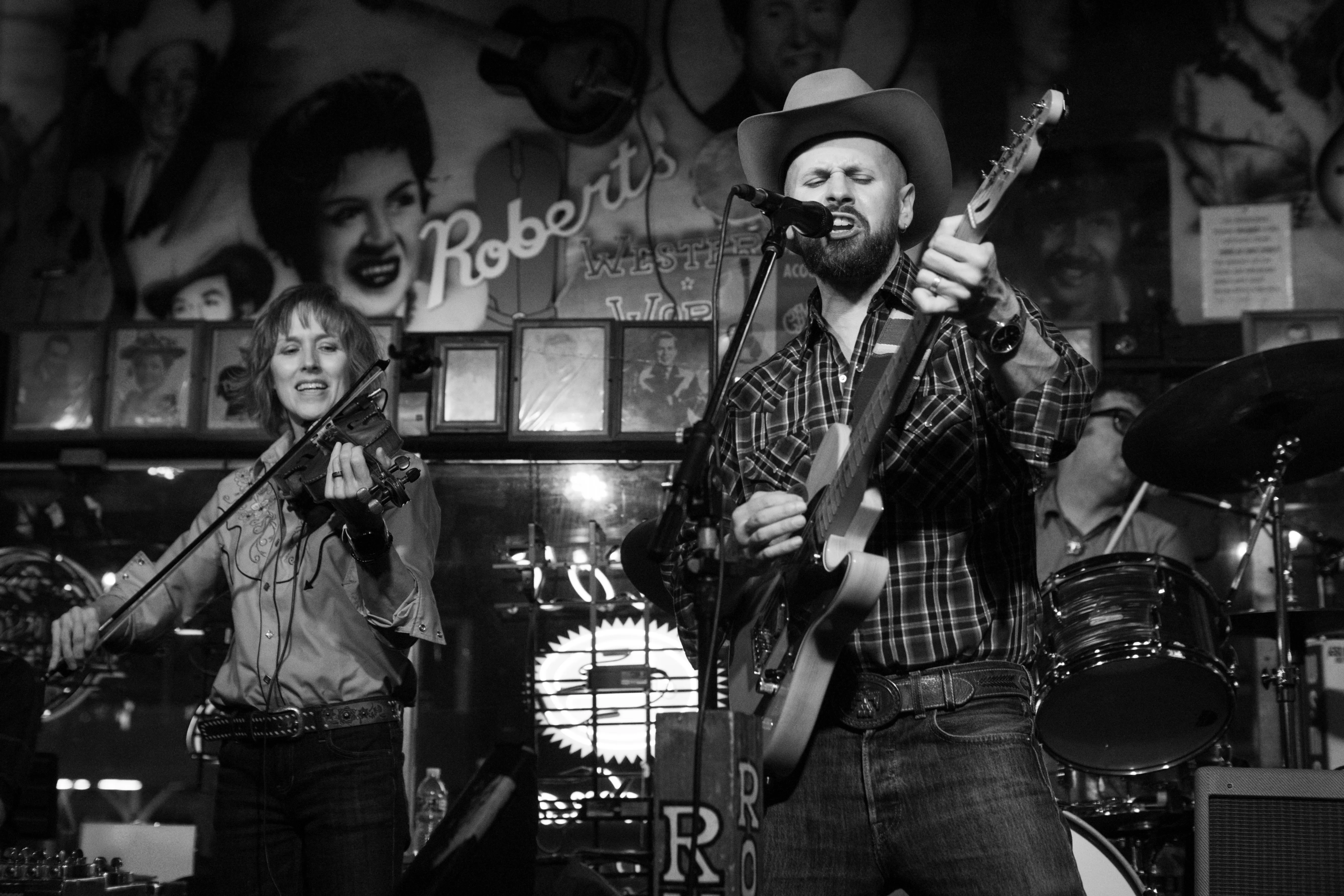 A singer in a cowboy hat strumming his guitar at Robert's Western World.