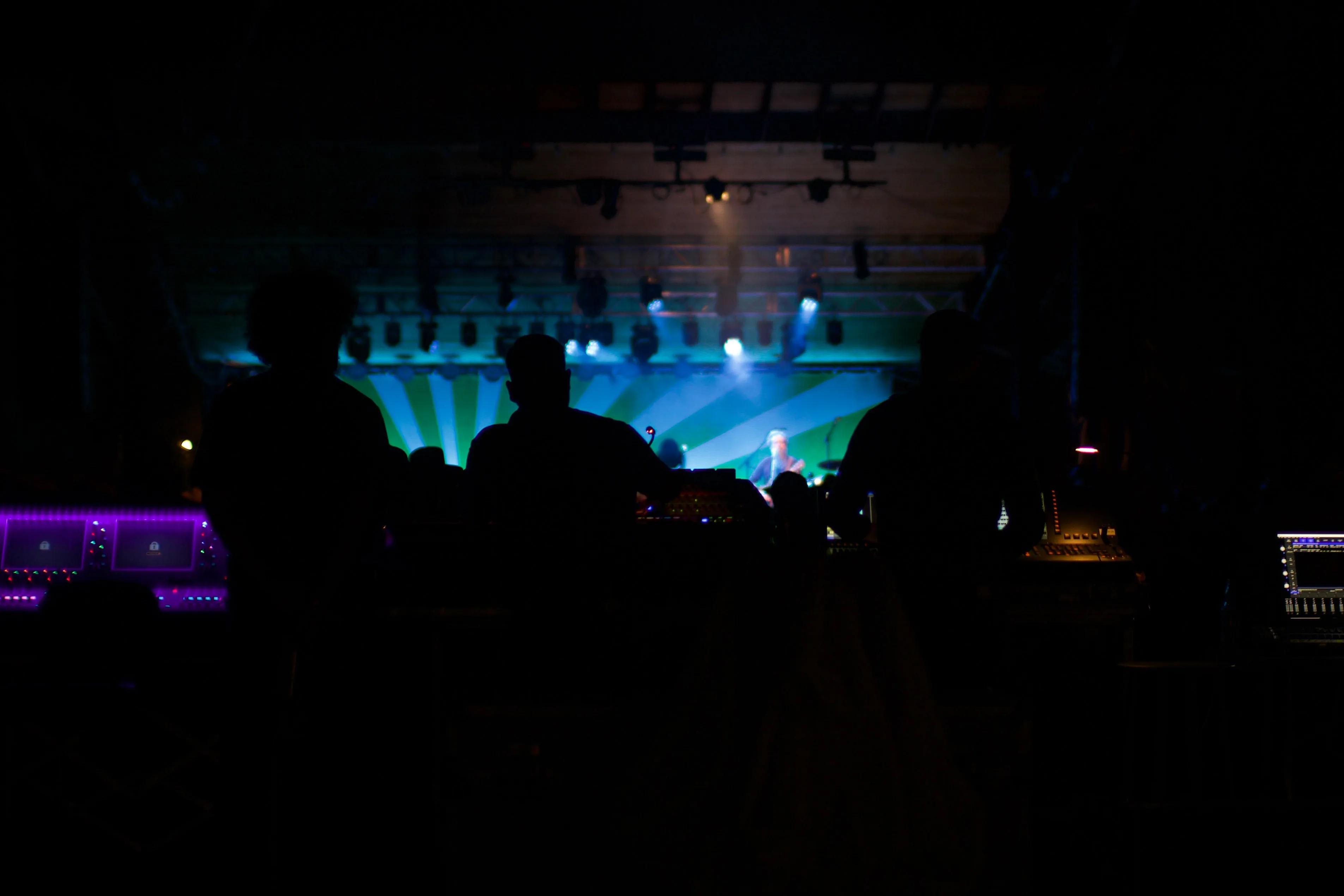 Three soundmen at a concert silhouetted against the stage lights.