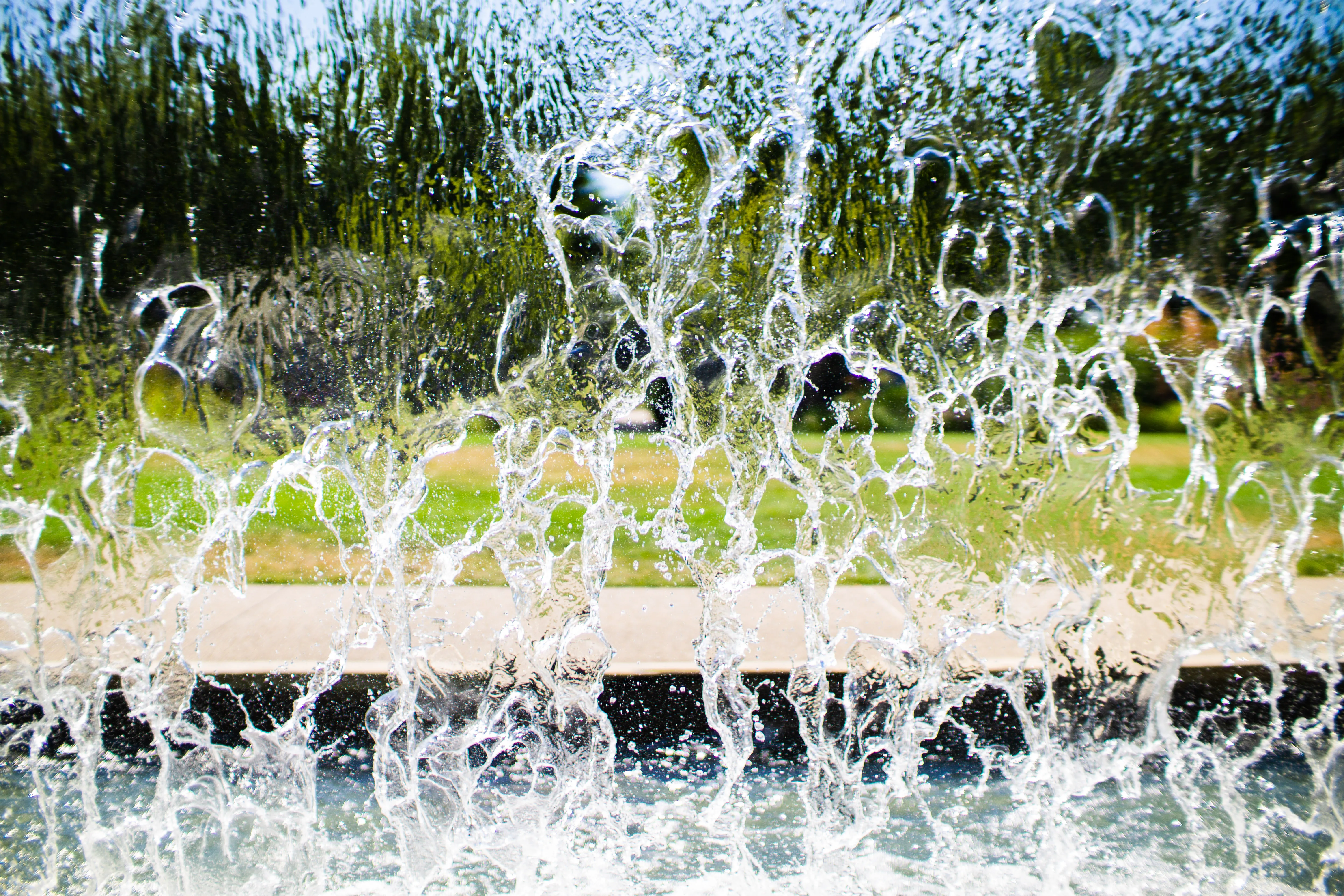 A waterfall with a sidewalk and lawn beyond.